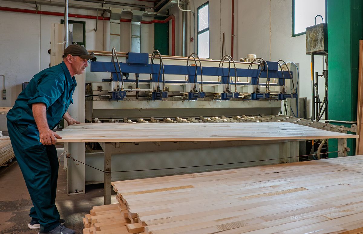 Worker at the edge-gluing press with a solid hardwood panel at SARAL