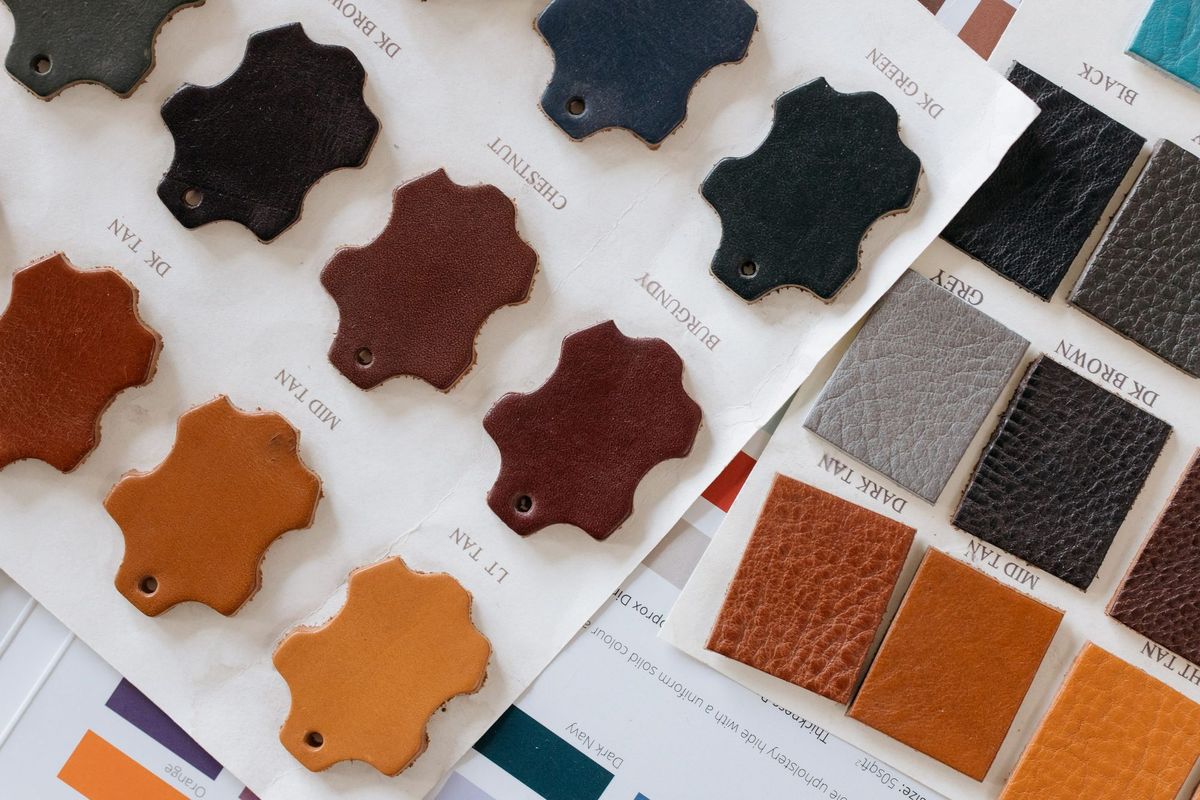 Leather sample cards in tan, burgundy, black and grey laid over a colour chart