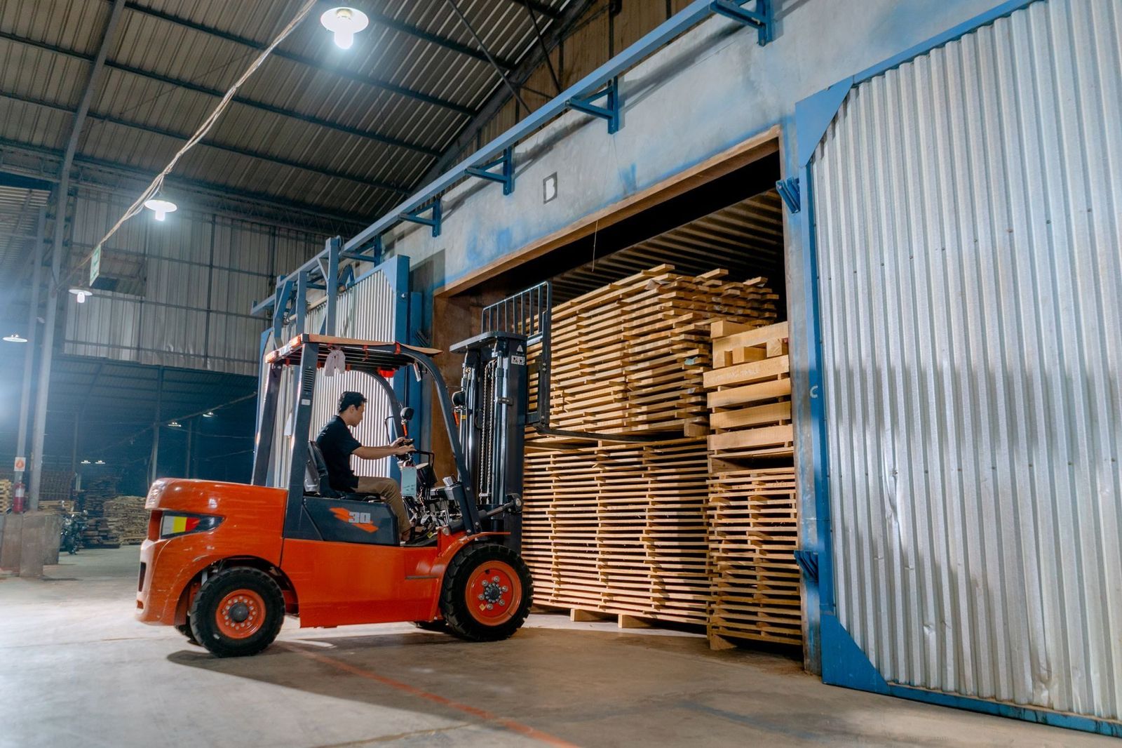 Truck laster strøstabler med skurlast inn i et industrielt tørkekammer for trelast