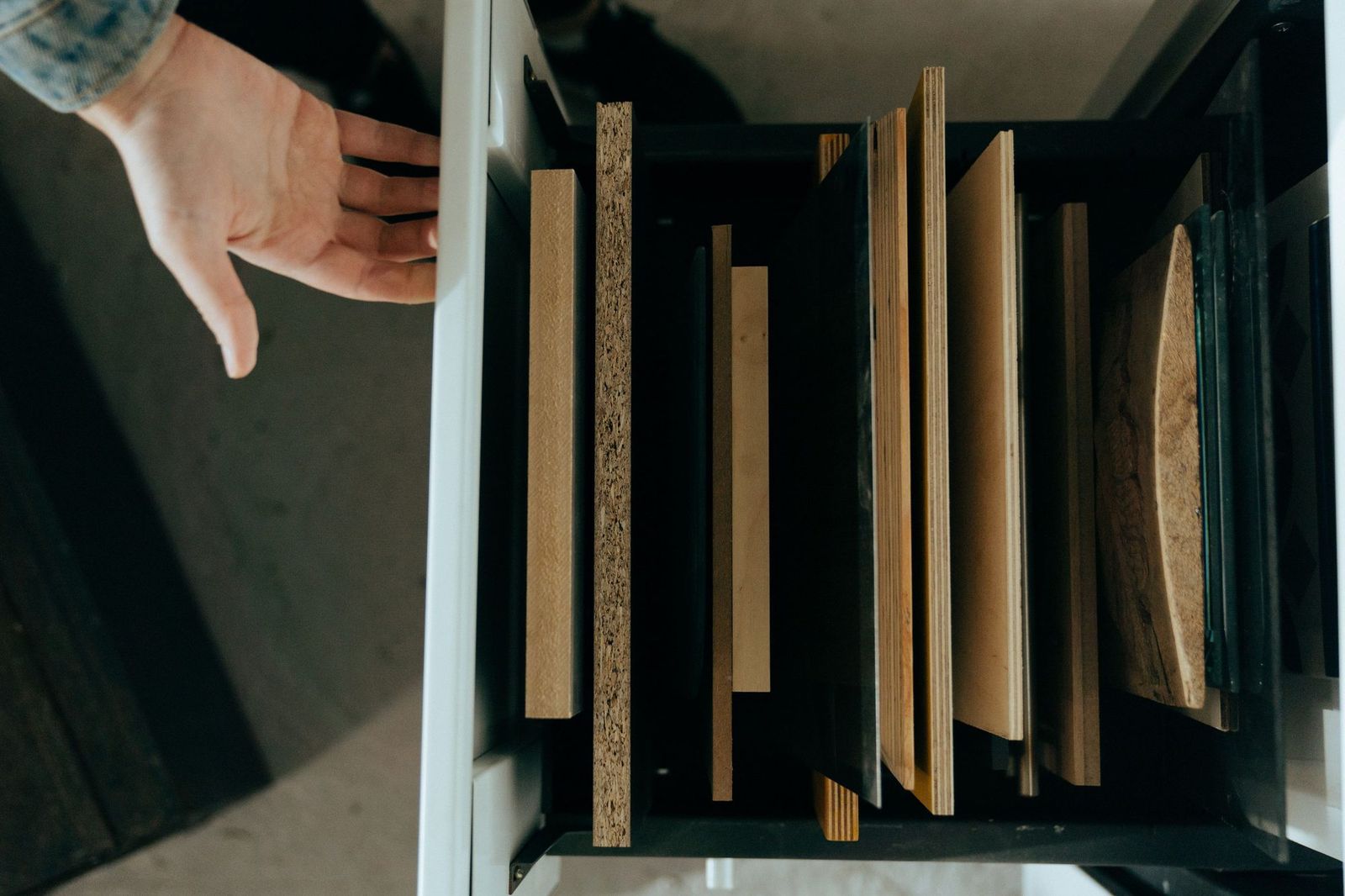 Edges of MDF, particleboard, plywood and solid wood samples standing side by side in a drawer