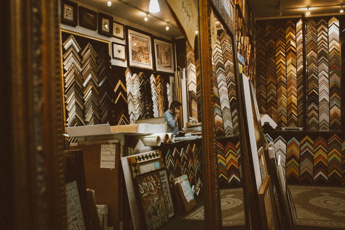Atelier de înrămare cu pereți plini de colțuri-mostră din profile de rame și tablouri înrămate