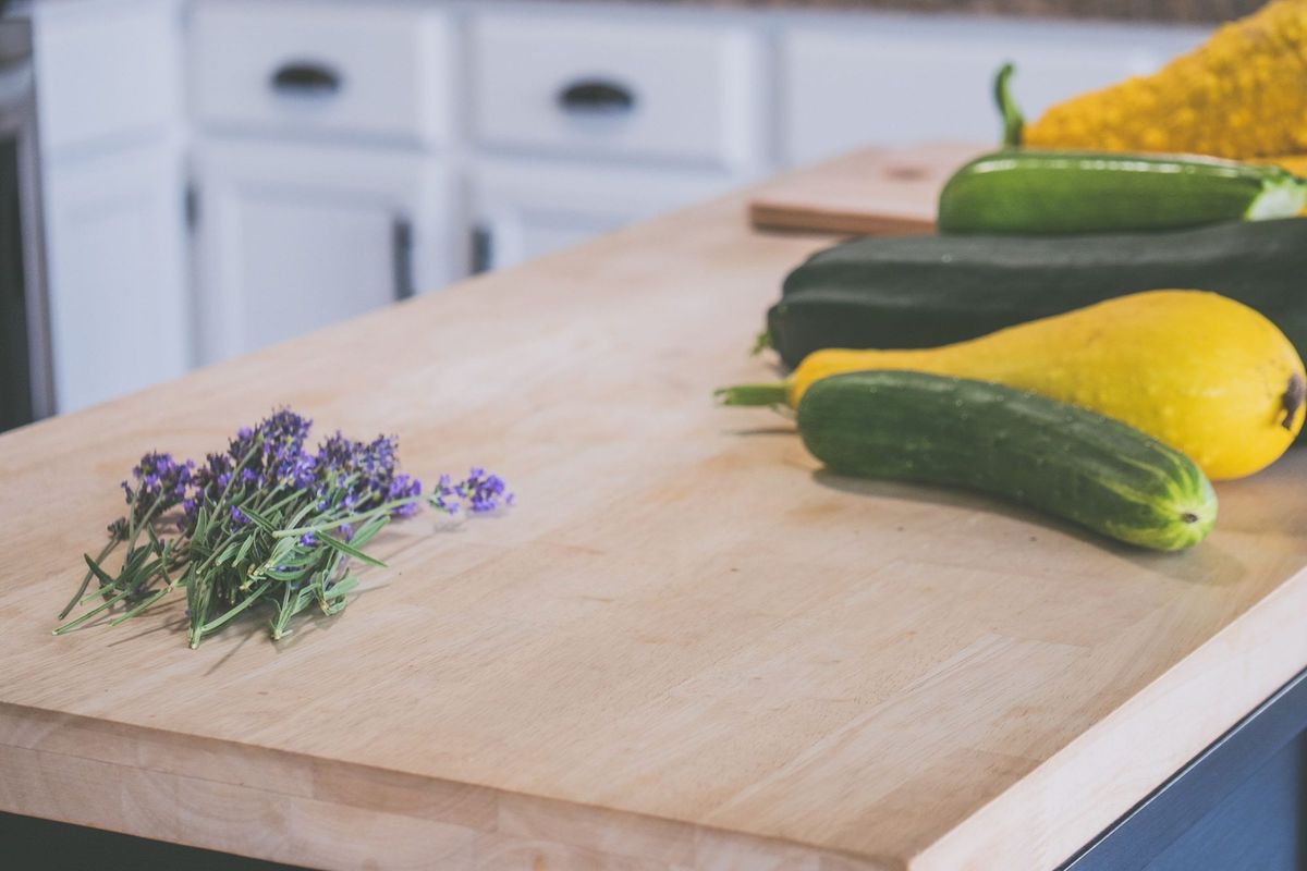 Light solid wood butcher-block worktop with courgettes, squash and a sprig of lavender