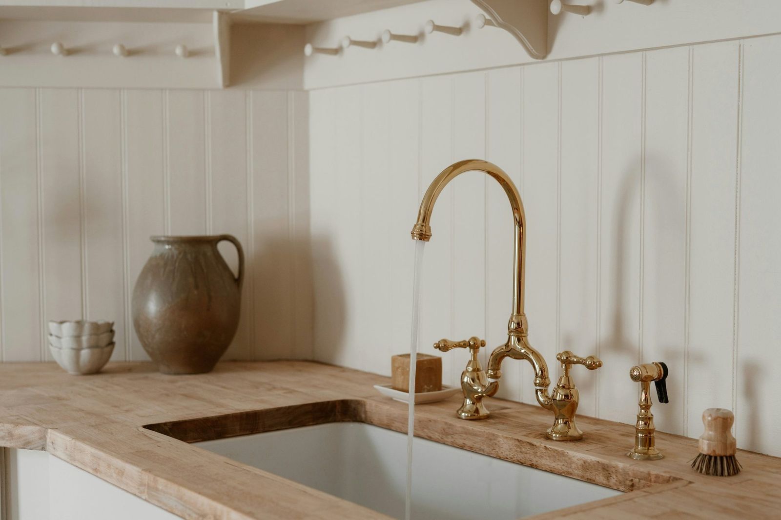 Solid wood kitchen worktop with an undermount ceramic sink and a brass bridge tap