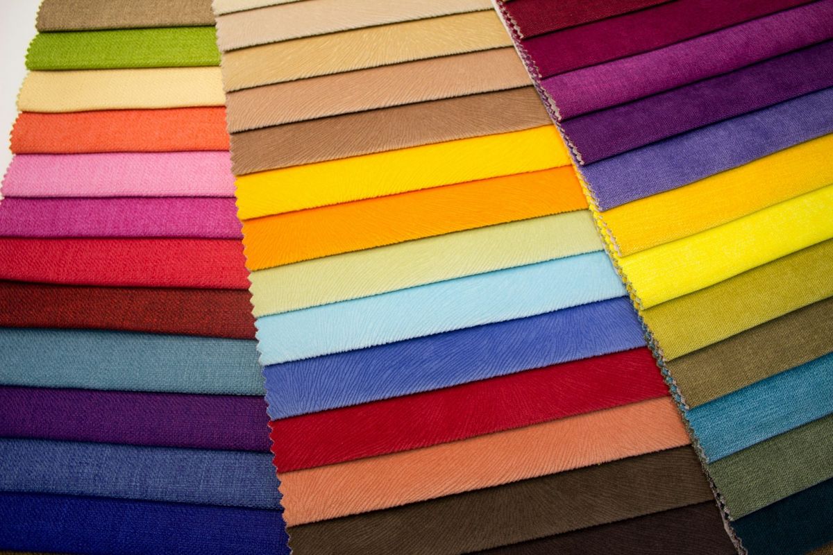 Stack of woven upholstery fabric samples in red, blue, grey and beige