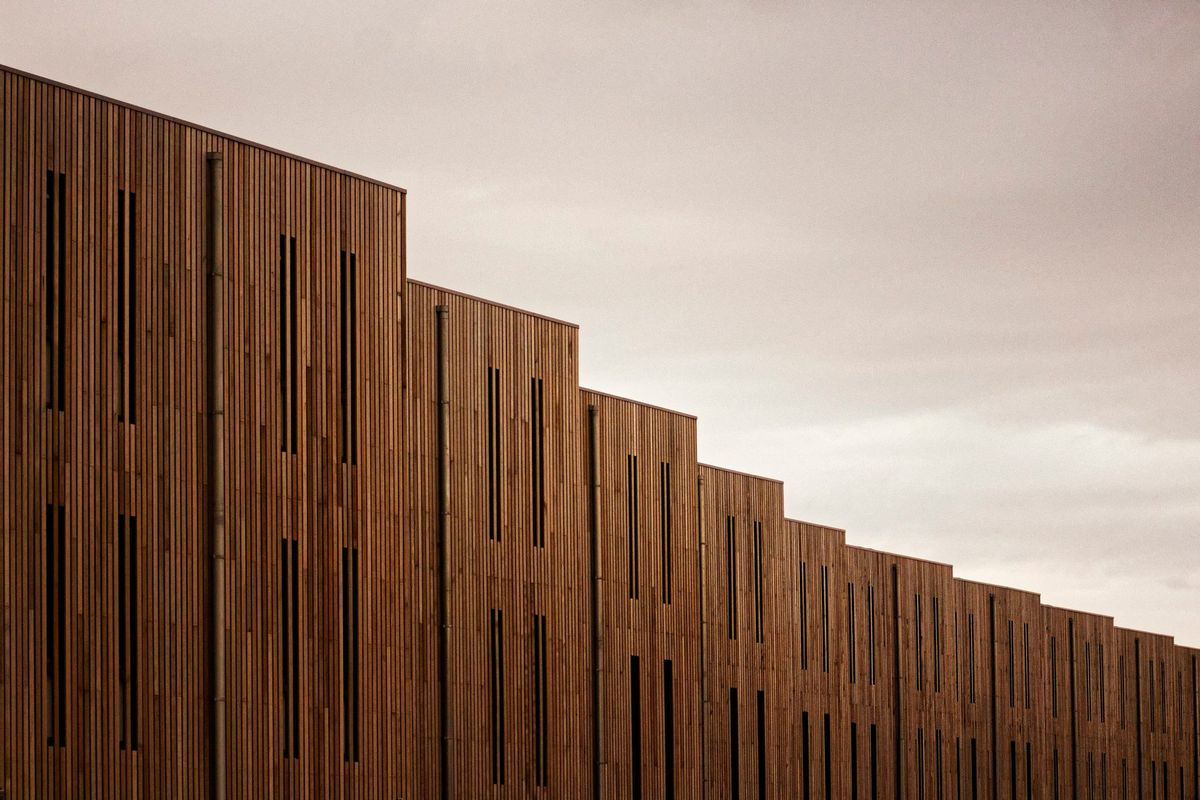 Modern building façade clad in vertical timber slats under an overcast sky
