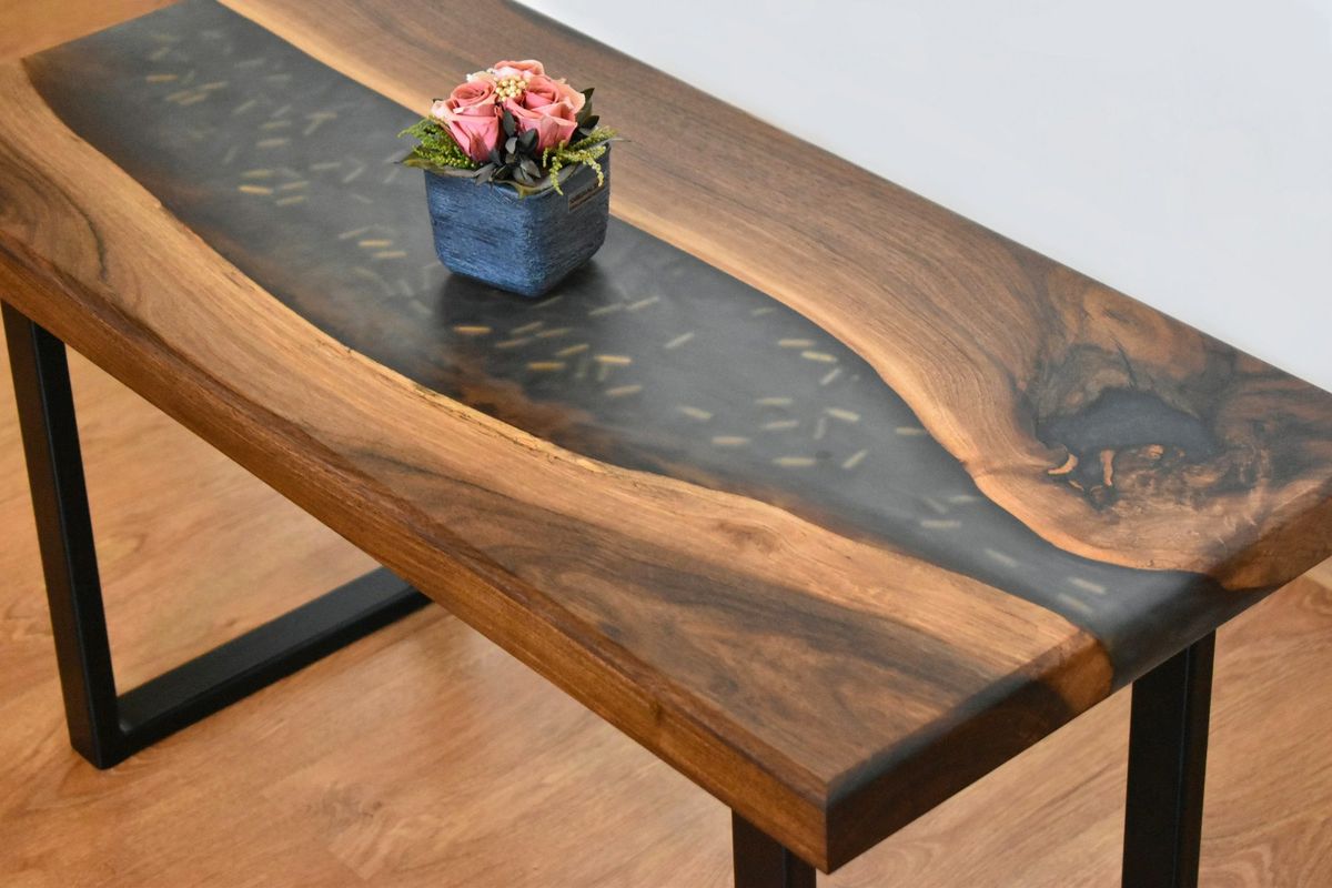 Walnut river table with a dark epoxy resin channel and black steel legs